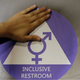 A new sticker is placed on the door at the ceremonial opening of a gender neutral bathroom at Nathan Hale High School in Seattle, May 2016. Photo via AP